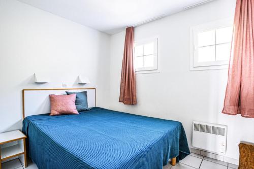 une chambre avec un lit bleu et deux fenêtres dans l'établissement Résidence le Hameau de Cap Esterel - maeva Home - Appartement 2 Pièces 5 Personnes - Sélection MAE-8433, à Saint-Raphaël