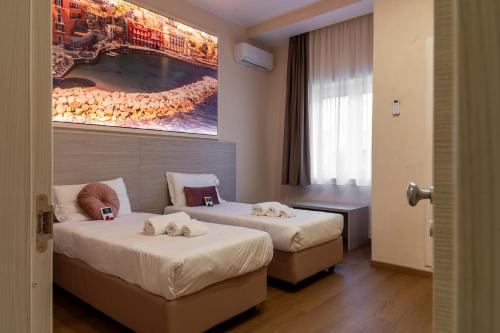 a hotel room with two beds and a painting on the wall at THE SUN HOTEL BOUTIQUE NAPOLI in Naples