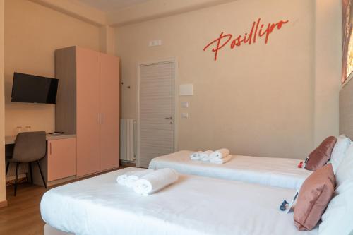 two beds in a room with a sign on the wall at THE SUN HOTEL BOUTIQUE NAPOLI in Naples