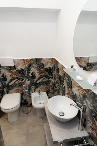 a bathroom with a sink and a toilet and a mirror at THE SUN HOTEL BOUTIQUE NAPOLI in Naples