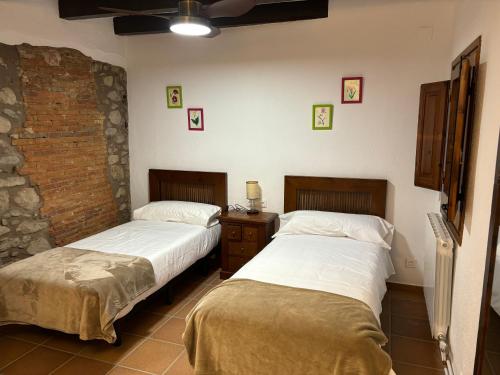 Habitación con 2 camas y pared de ladrillo en Masía Can Janet, en Arbúcies