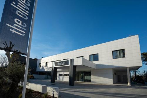 un edificio blanco con un cartel delante en The Oliver Apartamentos Aravaca, en Madrid