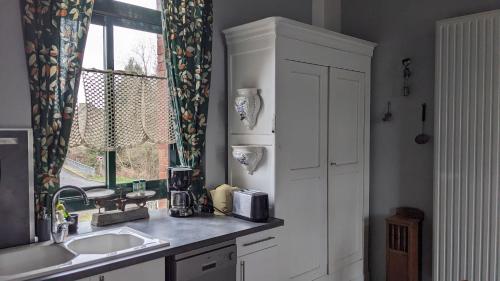 une cuisine avec un évier et une fenêtre dans l'établissement APPART' DU CHEF DE GARE gîte à Gouarec au pied de la Vélodyssée, à Gouarec