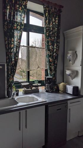 une cuisine avec un évier et une fenêtre dans l'établissement APPART' DU CHEF DE GARE gîte à Gouarec au pied de la Vélodyssée, à Gouarec