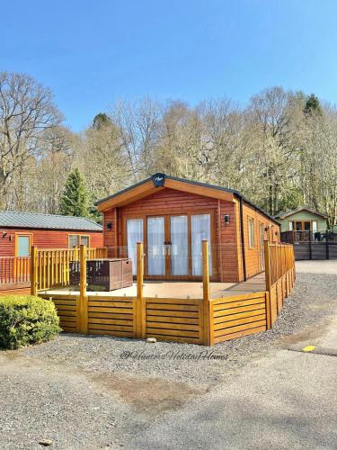 a large wooden cabin with a fence around it at Windermere View Lodge - White Cross Bay in Windermere