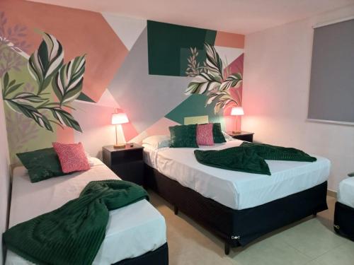 2 camas en una habitación con paredes de color verde y rosa en Pousada Costa Del Sol, en Búzios