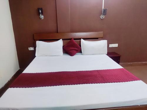 a bedroom with a bed with white and red pillows at Hotel Sea Sunrise in Calangute