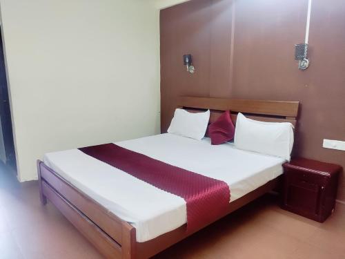 a bedroom with a bed with white sheets and red pillows at Hotel Sea Sunrise in Calangute