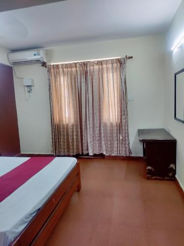 a bedroom with a bed and a window with curtains at Hotel Sea Sunrise in Calangute