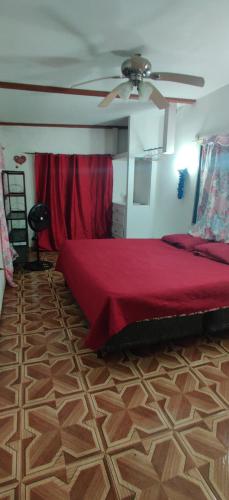 a bedroom with a red bed and a ceiling fan at Apartamento de tranquilidad. in La Ceiba