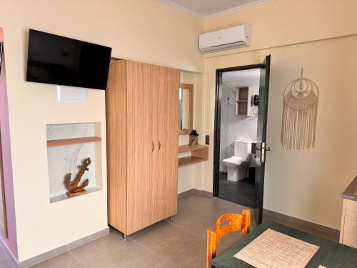 a room with a toilet and a television on a wall at Callista sea view or garden in Kissamos