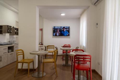 a restaurant with tables and chairs and a tv on the wall at THE SUN HOTEL BOUTIQUE NAPOLI in Naples