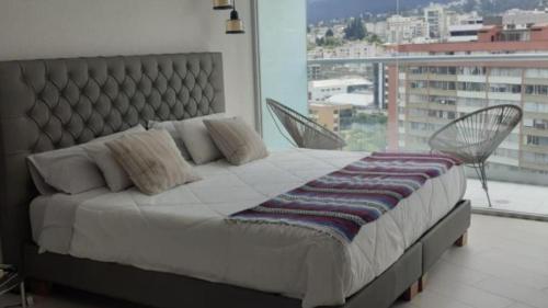 een slaapkamer met een groot bed en een groot raam bij ONE Luxury Views Suite Terrace La Carolina Park Heated Pool & Jacuzzi in Quito