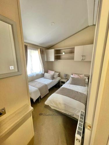 a small room with two beds and a window at Windermere View Lodge - White Cross Bay in Windermere