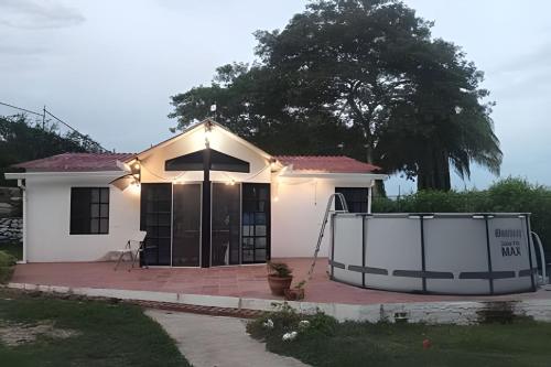 una pequeña casa blanca con una puerta delante en Cabaña Campestre de con piscina, cocina, y wifi., en Carmen de Apicalá