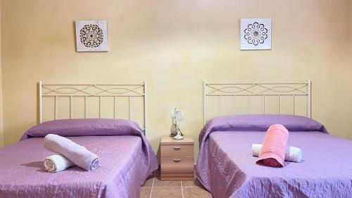 2 camas en un dormitorio con sábanas y almohadas púrpuras en CASA RURAL G, en Elche de la Sierra