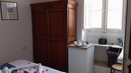 a bedroom with a large wooden cabinet next to a window at Corto Maltese Guest House in Cospicua