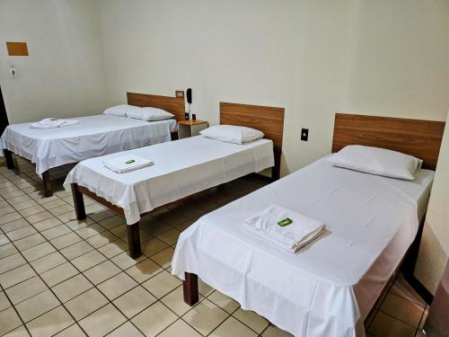 two beds in a room with white sheets at Hotel Vivenda das Cachoeiras in Brotas