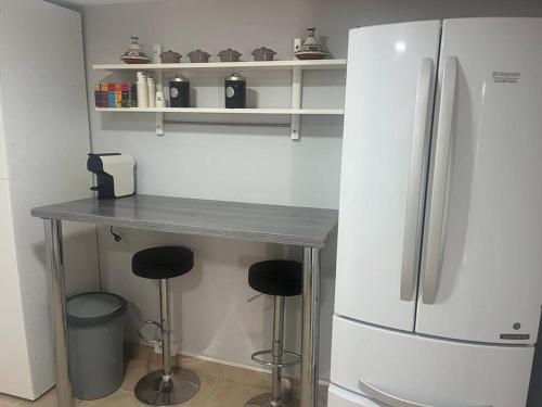- une cuisine avec un comptoir, un réfrigérateur et des tabourets dans l'établissement Maison indépendante, à Gaillon