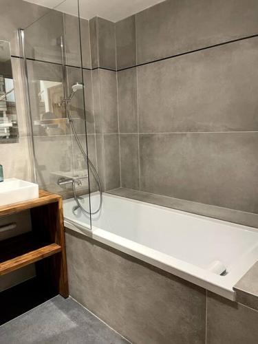 La salle de bains est pourvue d'une douche et d'une baignoire blanche. dans l'établissement Les logis du Parc, à Bullion