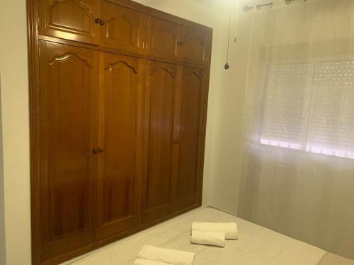 a bedroom with a wooden cabinet and two folded towels at Chalet el castillo in Dos Hermanas