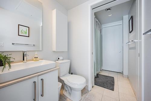 Baño blanco con aseo y lavamanos en Downtown Apartments 3, en Toronto