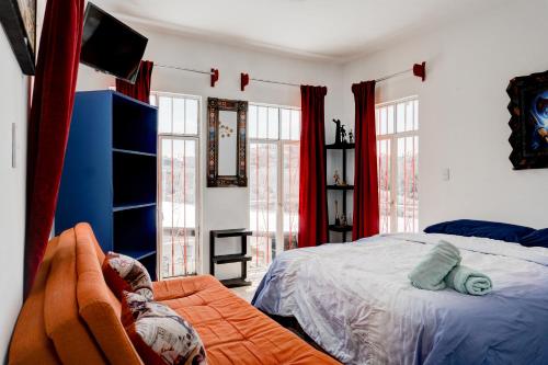 Schlafzimmer mit einem Bett, einem TV und Fenstern in der Unterkunft Casa Palaxs in Guanajuato