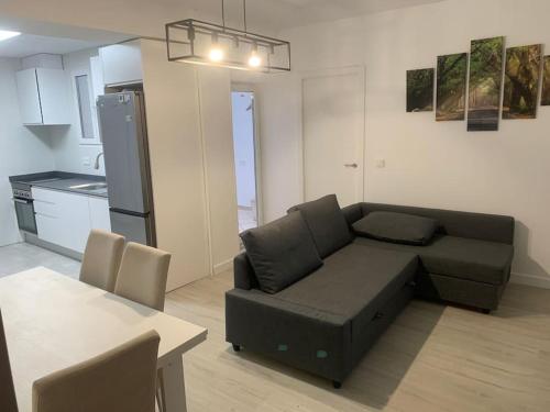 a living room with a black couch and a kitchen at Aerofira Paterna in Paterna