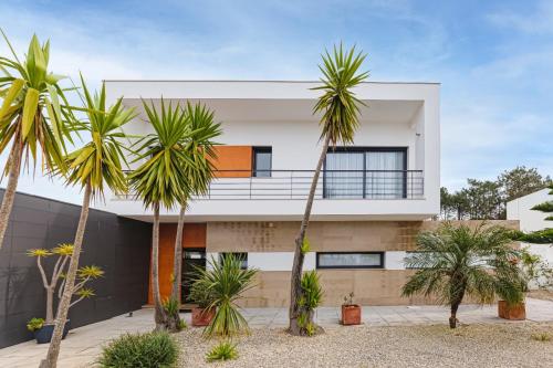 a house with palm trees in front of it at Maresia Villa Mar in Nazaré