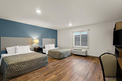 een hotelkamer met 2 bedden en een televisie bij WoodSpring Suites Fort Collins in Fort Collins