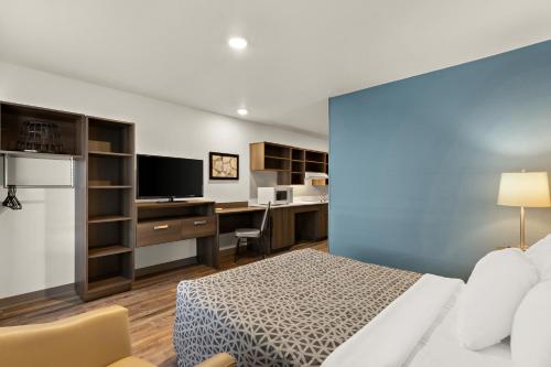 a bedroom with a bed and a desk with a computer at WoodSpring Suites Fort Collins in Fort Collins