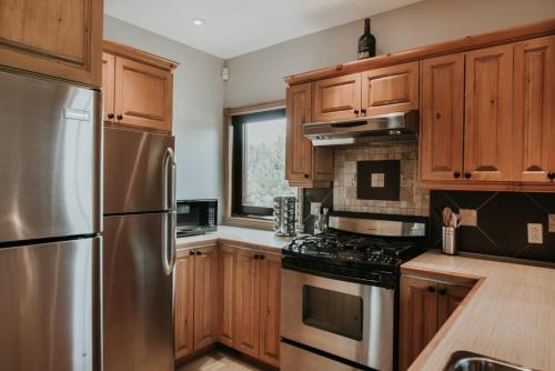 a kitchen with wooden cabinets and a stainless steel refrigerator at Royal Laurentien in Mont-Blanc