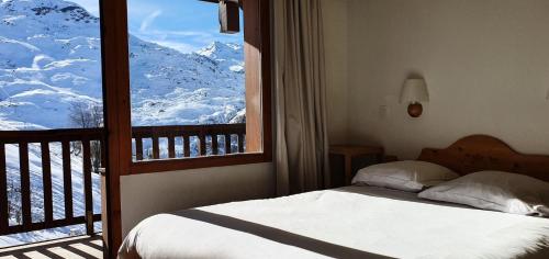 Un dormitorio con una cama y una ventana con montañas cubiertas de nieve en Résidence Les Valmonts - maeva Home - Appartement 4 Pièces 8 Personnes - Séle 41, en Saint-Martin-de-Belleville