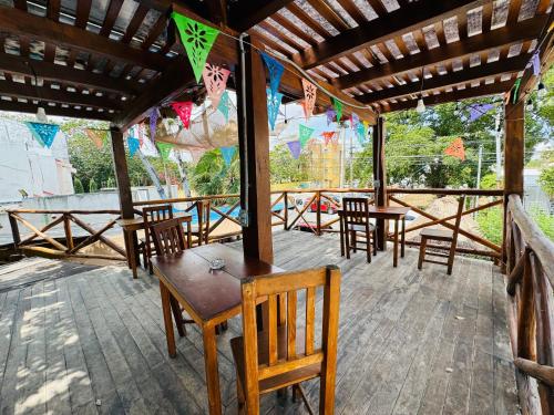eine Terrasse mit Holztischen und -stühlen und einem Dach in der Unterkunft La Luz Hostal Cancun in Cancún