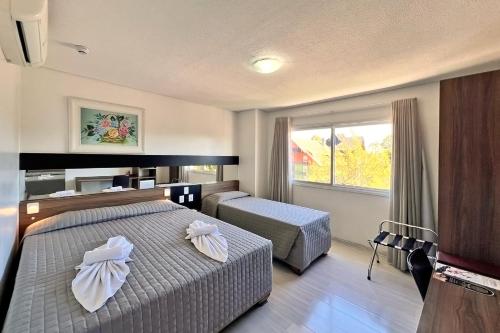 una camera d'albergo con due letti e una finestra di Sky Premium Hotel Gramado - Ótima Localização a Gramado