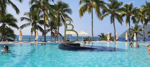 une piscine avec des palmiers et des gens dans l'eau dans l'établissement Turquoise studio remarquable vue mer, au Diamant