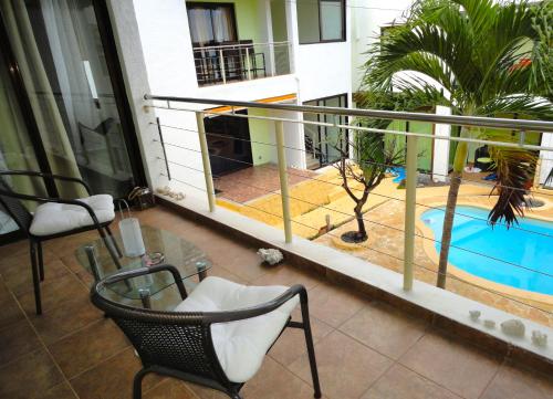 balcón con mesa y sillas y piscina en Residence Ciel Bleu, en Flic en Flac