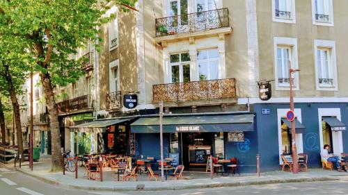 a building with tables and chairs on a city street at Bel écrin sur l'île de Nantes - GARE TGV, CHU, CONGRES in Nantes