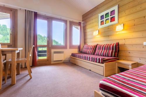 um quarto com um sofá, uma mesa e uma janela em Résidence Plagne Lauze - maeva Home - Appartement 3 Pièces 7 Personnes - Séle 14 em Mâcot La Plagne