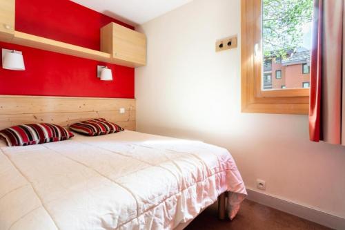 a bedroom with a bed with a red wall at Résidence Plagne Lauze - maeva Home - Appartement 2 Pièces 5 Personnes - Sélection MAE-4054 in Mâcot La Plagne
