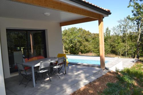 un patio avec une table et des chaises et une piscine dans l'établissement Gite avec piscine privée et climatisation à Cahors, à Cahors