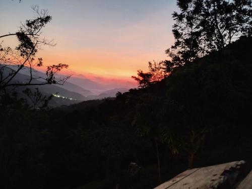 Blick auf den Sonnenuntergang von einem Hügel mit Bäumen in der Unterkunft REFUGIO EN EL BOSQUE in Cisneros