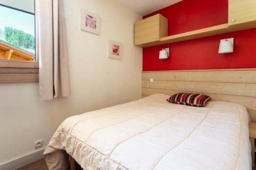 um quarto com uma cama com uma parede vermelha em Résidence Plagne Lauze - maeva Home - Appartement 2 Pièces 5 Personnes - Séle 74 em Mâcot La Plagne