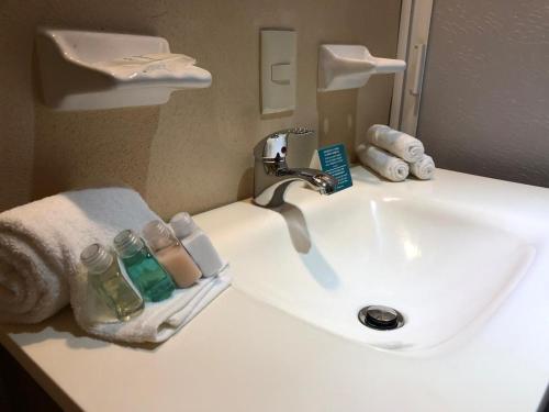 サユリタにあるPacific Inn hotelの白いバスルーム(洗面台、蛇口、タオル付)