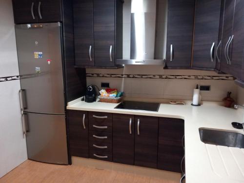 a kitchen with black cabinets and a stainless steel refrigerator at Apartamento los rosales in Letur