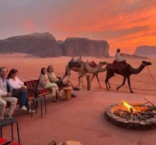 Un groupe de gens assis autour d'un feu dans le désert dans l'établissement Desert star camp, à Wadi Rum