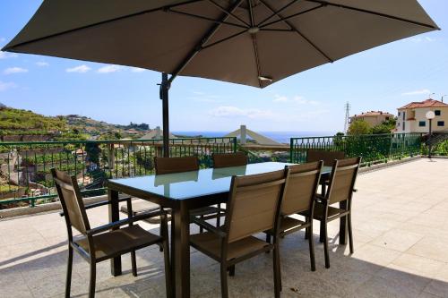 a table and chairs with an umbrella on a balcony at Villas Quinta da Lapa by AnaLodges in Câmara de Lobos