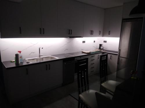 eine Küche mit weißen Schränken, einer Spüle und einer Lampe in der Unterkunft Down town house with uni sence! in Athen