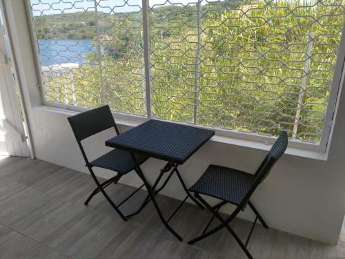 twee stoelen en een tafel voor een raam bij Studio avec vue sur la mer terrasse amenagee et wifi a Le Robert in Le Robert