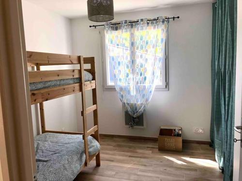ein Schlafzimmer mit zwei Etagenbetten und einem Fenster in der Unterkunft Jolie maison à 5 min de l'océan in Grayan-et-lʼHôpital
